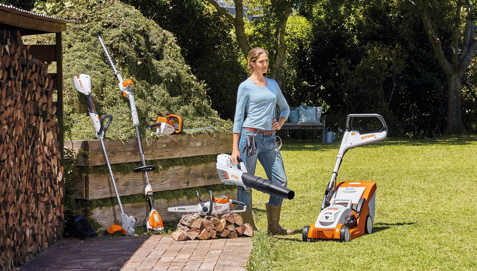 Woman standing in the garden with a selection of battery products from STIHL