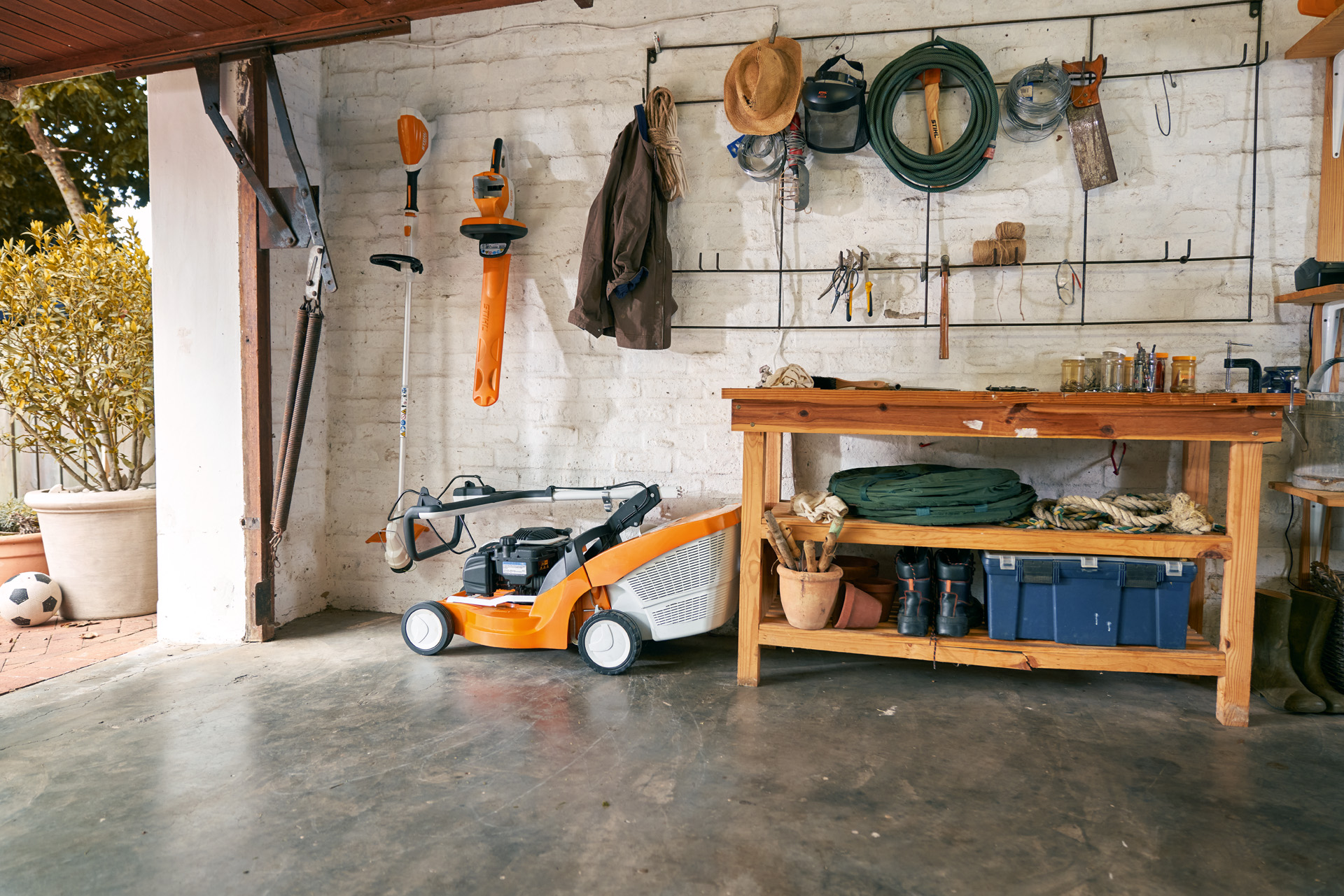 A woman wearing gloves folds down the handlebar of a lawn mower inside a tidy  